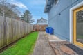Blue home exterior with fenced backyard featuring green lawn and concrete walkway in quiet residential neighborhood.