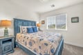 Your coastal-themed bedroom features a charming blue wood bed with seashell linens and warm bedside lighting for restful evenings.