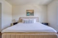 Sink into crisp white linens and plush pillows on your elegantly upholstered bed, perfectly positioned beneath coastal-inspired artwork that sets a serene, restful tone.
