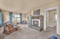 Cozy up in your welcoming living room featuring a stunning stone fireplace, plush seating, and natural light streaming through soft blue curtains.