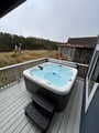 Soak in the brand new private hot tub on the deck, surrounded by coastal grasses and towering trees. The perfect spot to unwind after exploring the nearby shore.