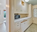 A bright, retro-style kitchen offers plenty of storage in cream cabinetry. The microwave and counter space make meal prep easy, while the cheerful floral curtain adds a homey touch.