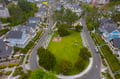 Aerial view of charming coastal neighborhood with colorful houses surrounding a peaceful community green space and tree-lined streets.