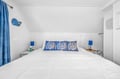 Drift off in this coastal-themed bedroom featuring crisp white linens and charming blue coral pillows that bring ocean vibes to your restful retreat.