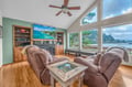 Your oceanfront living room invites relaxation with plush recliners, fireplace warmth, and panoramic water views through floor-to-ceiling windows.