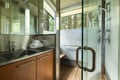 Your sleek bathroom features modern fixtures and a glass shower with forest views for a serene bathing experience.