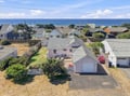 Aerial view of a charming coastal property situated in a peaceful beach neighborhood, with the ocean just moments away beyond the residential streets.
