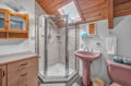 Refresh in your charming attic bathroom with exposed wood beams, skylight, and modern shower for a cozy retreat.