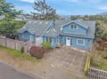 Charming blue coastal home with spacious driveway and privacy fence, nestled in a peaceful residential neighborhood near the ocean.