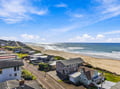 Aerial view showing the property's coastal location with direct beach access and surrounding neighborhood along the scenic shoreline.