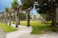 Peaceful garden walkway featuring rustic wooden pergola and well-maintained grounds in a charming neighborhood setting.