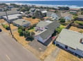 An aerial view of the property nestled in a quiet coastal neighborhood, with sandy beaches and rolling ocean waves just steps away.