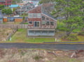 A distinctive cedar-shingled coastal home featuring expansive windows and a wraparound deck, situated in a quiet residential neighborhood near the waterfront.