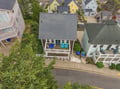 Aerial view of this charming property nestled in a peaceful residential neighborhood, featuring spacious double-deck porches with inviting turquoise seating where you can relax and enjoy the coastal atmosphere.