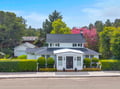 Charming white colonial home nestled among mature trees and manicured landscaping in a peaceful neighborhood setting.