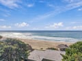Coastal retreat nestled among evergreen-covered dunes overlooking a pristine stretch of sandy beach and sparkling turquoise ocean waves.