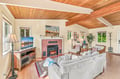 Unwind in your inviting living room beneath soaring wood ceilings, where a cozy fireplace and plenty of natural light create the perfect setting for relaxing evenings together.