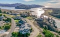 Aerial view of coastal residential community nestled between forested hills and tidal estuary waters.