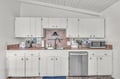 Your fully equipped kitchen features white cabinets, stainless steel appliances, and a charming brick backsplash perfect for preparing meals during your stay.
