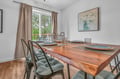 Gather around your beautiful wood dining table, perfectly set for memorable meals with loved ones in this bright, inviting space.