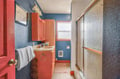 Step into your vibrant bathroom featuring coral cabinets and blue walls that create a cheerful, energizing space for your morning routine.