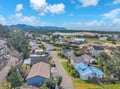 Aerial view of a charming coastal community nestled between forested mountains and scenic waterways, offering peaceful small-town living.