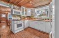 Your fully equipped kitchen features white cabinets, modern appliances, and warm wood ceilings that create the perfect space for home-cooked meals.