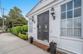 Charming white building facade with elegant dual entrances, decorative lanterns, and manicured landscaping in a peaceful residential setting.