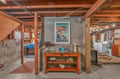 Discover your own creative retreat in this charming basement workshop, complete with vintage beach artwork and rustic wooden beams overhead.