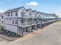 Modern row of waterfront townhomes with private balconies and convenient parking, offering a peaceful coastal community setting.