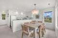 Bright open-concept kitchen and dining area with elegant chandelier lighting, spacious table seating for gatherings, and large windows framing peaceful neighborhood views.