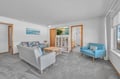 Unwind in your bright living room with coastal artwork, comfy seating, and a curated bookshelf for cozy reading moments.