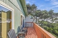 Step out onto your private balcony where the morning sun warms the wooden deck and coastal pines frame peaceful views of the natural surroundings beyond.