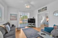 Relax in your bright living room with plush seating, a ceiling fan, and glass doors opening to the balcony—a cozy retreat to unwind and enjoy the natural light streaming through.