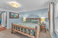 Settle into your cozy log bed with soft blue linens, surrounded by warm lighting and mountain art that creates a peaceful retreat.
