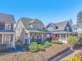 Charming coastal neighborhood with weathered shingle homes, manicured gardens, and classic American architecture under clear blue skies.
