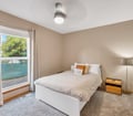 Unwind in your peaceful bedroom with soft neutral tones, a comfy bed, and natural light streaming through the window overlooking lush greenery.