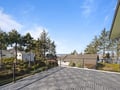 Spacious deck with stunning water views surrounded by evergreen trees and neighborhood homes under clear blue skies.