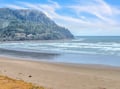Pristine sandy beach stretches along the coastline with forested hills rising dramatically from the shore.
