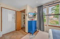 Your cheerful bedroom features tile flooring, charming blue furniture, and large windows framing peaceful neighborhood views—creating a bright, welcoming retreat for your stay.