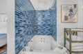 Soak in your private jetted tub surrounded by stunning blue mosaic tiles, with plush towels and artwork creating a spa-like retreat.