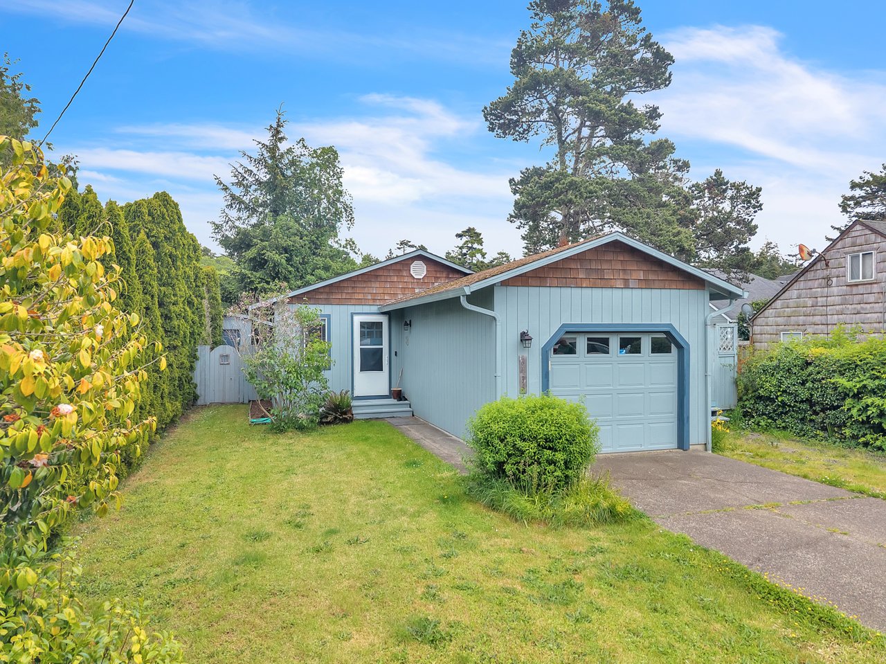 A charming coastal cottage nestled in a peaceful neighborhood, surrounded by mature trees and lush greenery, with convenient parking and nearby beach access.