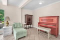 Your cozy living space features a comfortable mint green armchair and charming red piano, perfect for relaxing or creating music.