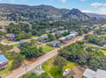 Aerial view showcases the property's peaceful neighborhood setting, nestled among rolling hills and lush greenery with mountain vistas in the distance.