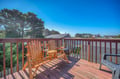 Relax on your private wooden deck with comfortable Adirondack chairs, where warm sunlight and peaceful neighborhood views create the perfect spot for morning coffee.