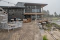 The property sits on a scenic waterfront, with a spacious deck overlooking natural coastal landscapes. String lights create an inviting ambiance for evening relaxation by the water.