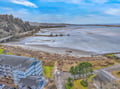 Aerial view of coastal vacation rental property situated near pristine beach with expansive ocean views and natural landscape.