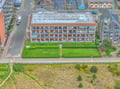 Aerial view of a beachfront property with colorful balconies, featuring well-maintained grounds and convenient coastal location.