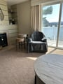 Picture yourself curled up with a book in that cozy armchair, sunlight streaming through tall windows revealing stunning lake views. The fireplace adds warmth while the balcony invites you to sip morning coffee overlooking the water.