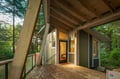 Stunning modern forest retreat with exposed beams and floor-to-ceiling windows that frame the lush woodland setting perfectly.